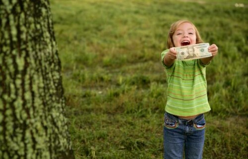 Beautiful happy little girl with dollar note on her hands