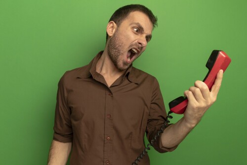 angry young caucasian man holding old telephone looking it screaming isolated green wall 2048x1365