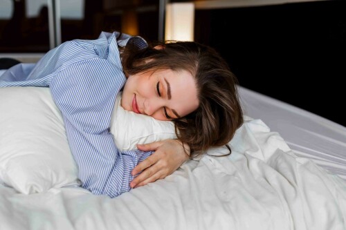 Cute woman lying  on her   stomach   on the bed and sleep . Wearing stylish black lingerie and striped  boyfriend shirt.